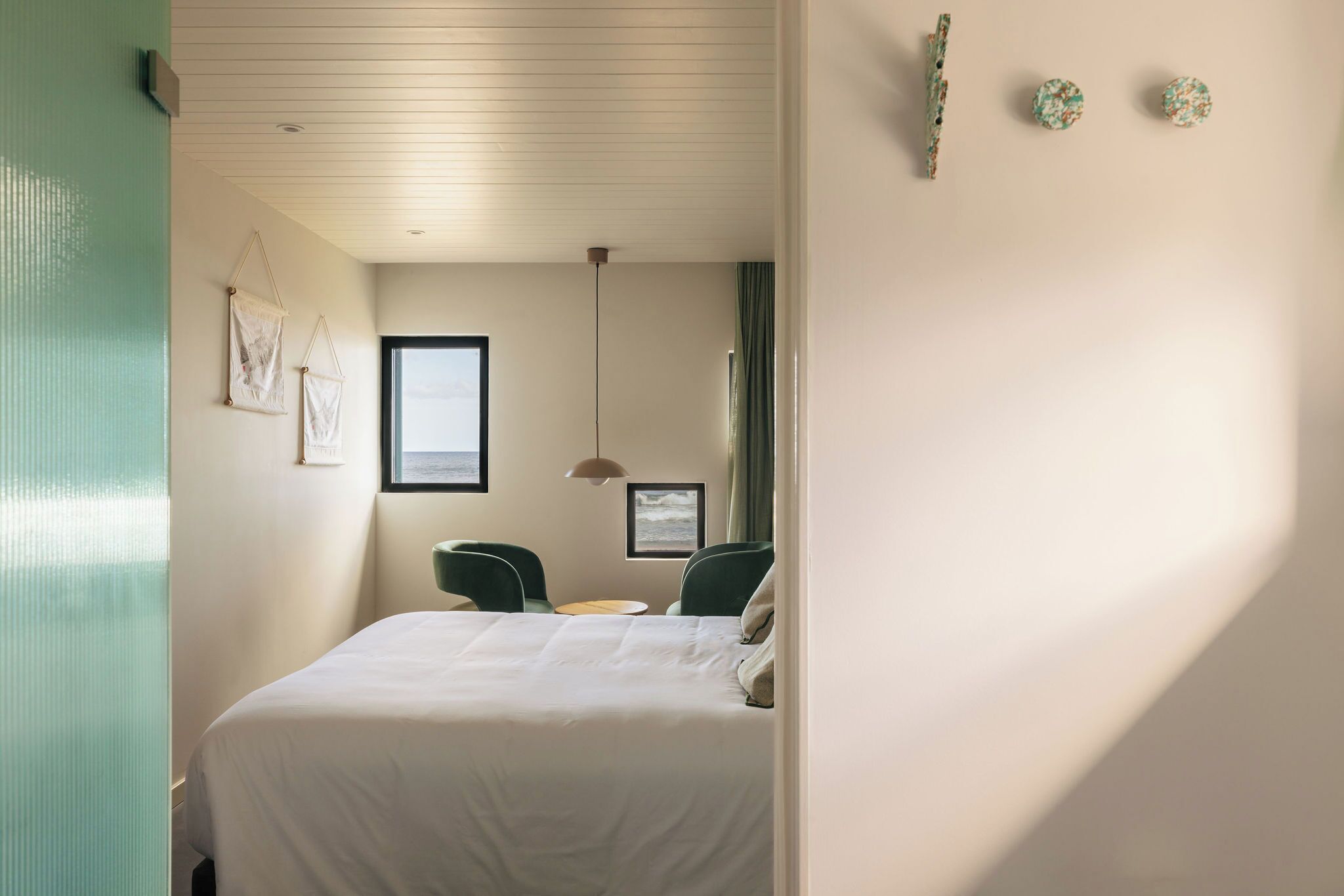 A hotel room with a bed, two chairs, a small table, and a window.