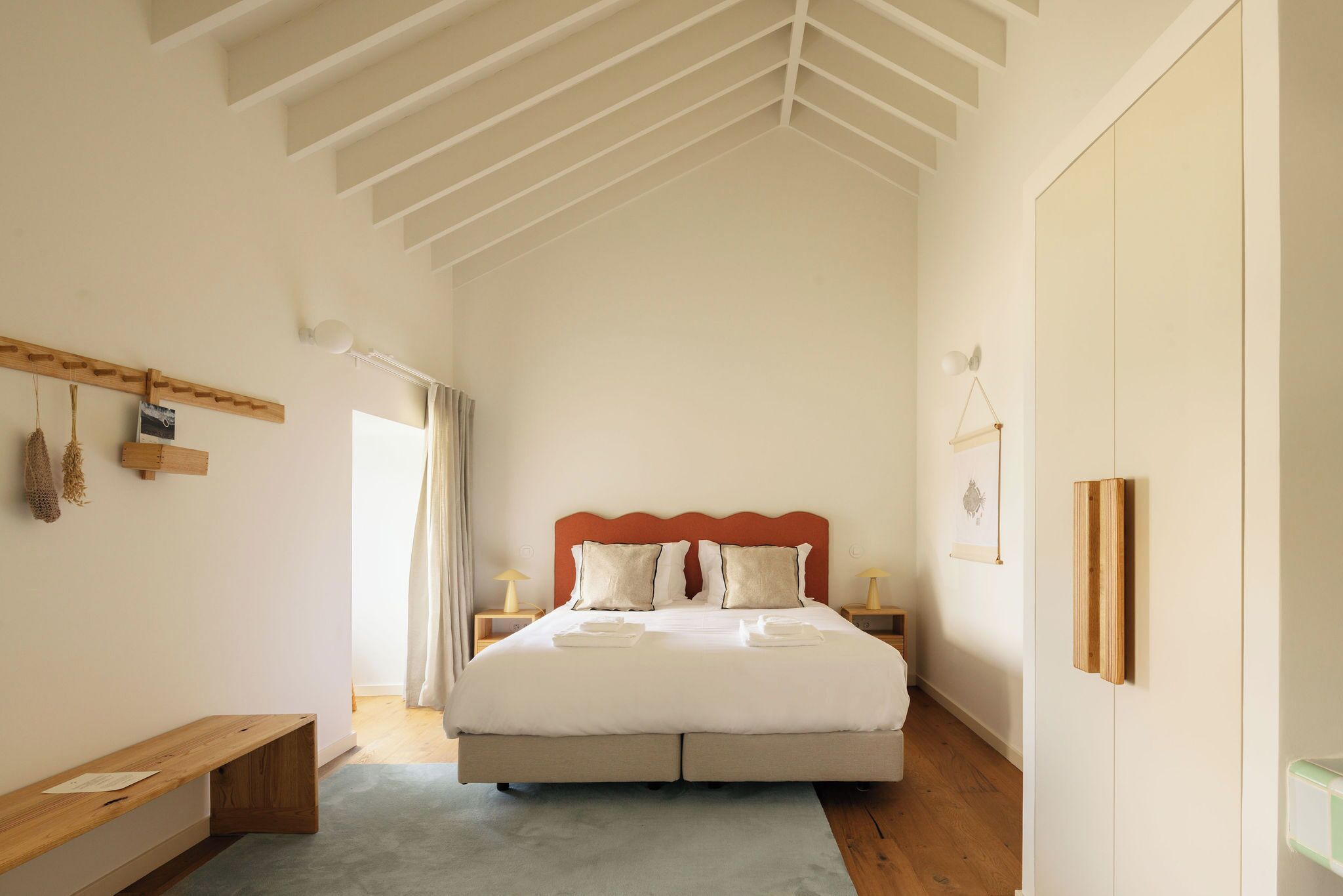 Una camera da letto con un letto grande, una testiera in legno, comodini, una panca e un armadio.