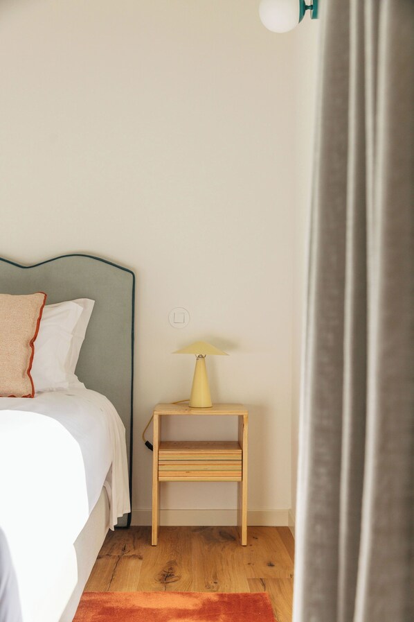 A bedroom with a bed, a bedside table with a lamp, and a wooden nightstand.