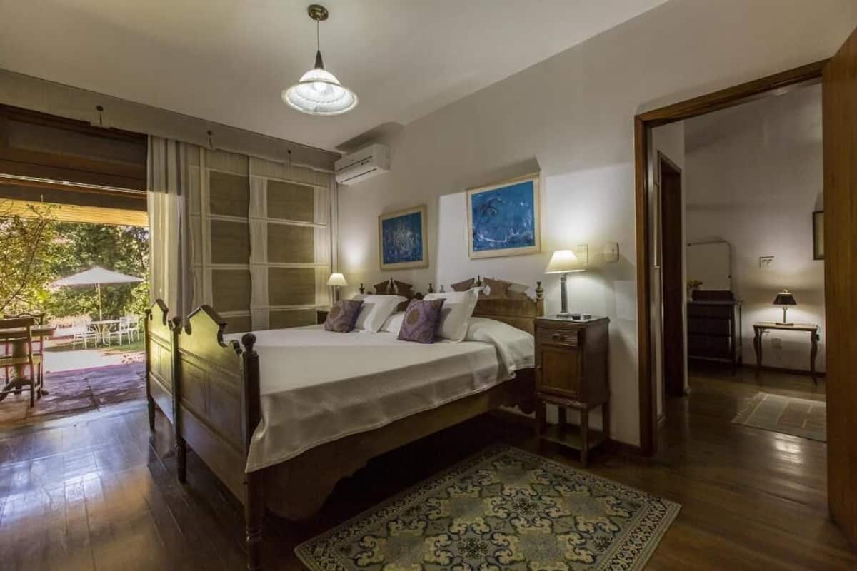 A bedroom with a wooden bed, bedside tables, a patterned rug, and artwork on the walls.