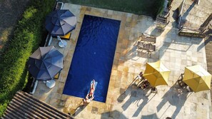 An aerial view of a rectangular swimming pool with tiled edges, surrounded by outdoor seating areas with umbrellas. - Hotel Colinas de Petropolis (Petrópolis)