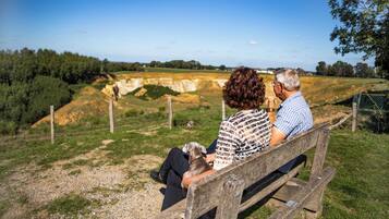 A couple sitting on a wooden bench overlooking a natural landscape with a fence and trees.