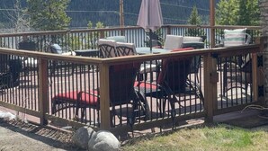 A deck with outdoor furniture, a table, and chairs, overlooking a mountainous landscape. - Lakeview Lodge - Gorgeous view of Grand Lake! (Grand Lake)