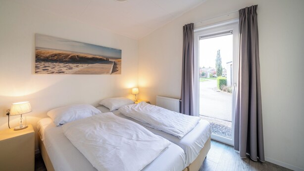 A hotel room with two beds, a painting on the wall, a window with curtains, and a view of the outside. - Ravenbosch Royal - Bath & Atmosph firepl (Valkenburg)