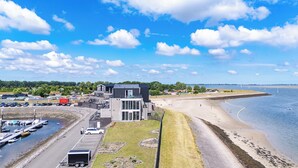 A coastal building with a parking area, a beach, and a marina.