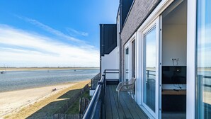 A balcony with a view of the beach and the sea.