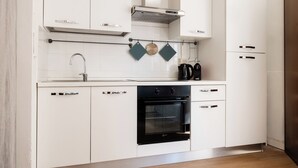 A modern kitchen with white cabinetry, a black oven, and a stainless steel range hood. - Montagnola Mini House (Rome)