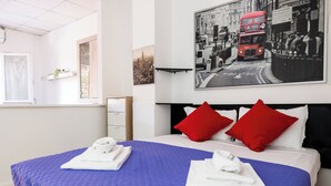 A hotel room with a large bed, two red pillows, and a cityscape photo on the wall. - Montagnola Mini House (Rome)