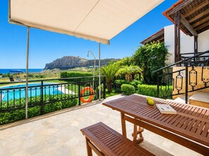 Ein Balkon mit Pool, einem Tisch mit Buch und Blick auf Meer und Berge.