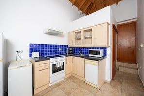 Cocina compacta equipada con estufa, horno, microondas y cafetera.
