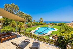 A pool with a geometric design, surrounded by a well-maintained lawn and a variety of trees.