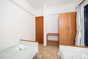 Un dormitorio con dos camas, un armario y una puerta.