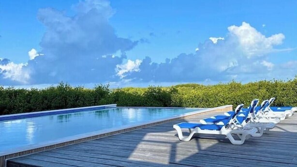 Una piscina con sillones de descanso y una terraza de madera.
