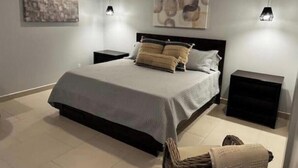Un dormitorio moderno con una cama grande, dos mesitas de noche y obras de arte abstractas en las paredes.