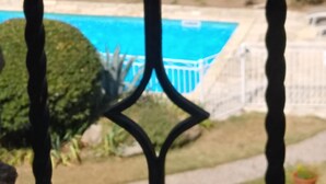 A view through a metal gate with a pool in the background.