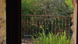 A balcony with a metal railing, a tiled floor, and a view of trees and greenery.