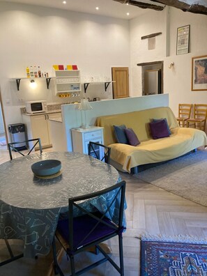 Un espace de vie compact comprenant une table à manger, un canapé, un coin cuisine et une petite table à manger avec des chaises.
