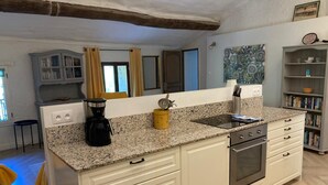 A kitchen with a granite countertop, a coffee maker, a sink, and a stove.