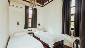 A room with two single beds, wooden floors, a ceiling fan, and a window with curtains. - Eski Yeni Tatil Evi (Kumluca)