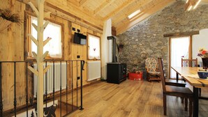 A wooden interior with a stone wall, a fireplace, and a dining area. - Baita La Ciamorza Near Dolomiti - Veneto (Lozzo di Cadore)