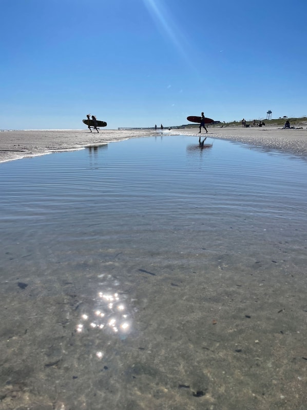 A beach with clear shallow water, a pier in the background, and people walking with surfboards. - Four Bedroom Beach House - Walk to Park and Beach (Isle of Palms)
