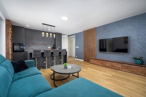 A modern living room with a sofa, a round coffee table, and a TV mounted on the wall.
