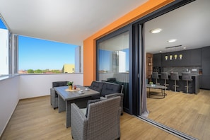 A balcony with wicker furniture, a kitchen with bar stools, and a sliding glass door.
