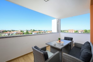 Un balcon doté de meubles en osier, d’une table et offrant une vue sur les bâtiments.