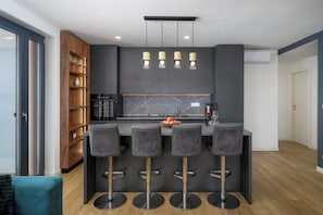 Une cuisine moderne dotée d’un îlot central, de tabourets de bar et de luminaires suspendus.