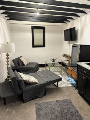 A compact living space with a sofa, a TV, a small table, and a cabinet.