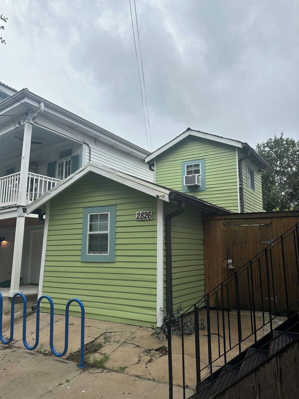 A green house with a porch, a number '2826' on the side, and a wooden fence.