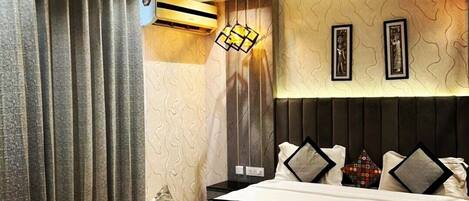 A modern hotel room with a large bed, a sofa, and a unique wall-mounted light fixture.