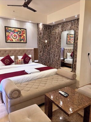 A modern hotel room with a large bed, a sofa, a coffee table, and a ceiling fan. - The Origin Suites (Lucknow)