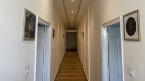 Un pasillo con suelo de madera, paredes blancas y puertas decoradas con cuadros.
