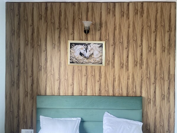 A room with a wooden wall, a framed picture of horses, and a green headboard. - Hotel Nirmal - Budget Friendly Rooms near Fortis Hospital and Marriage Palaces (Amritsar)