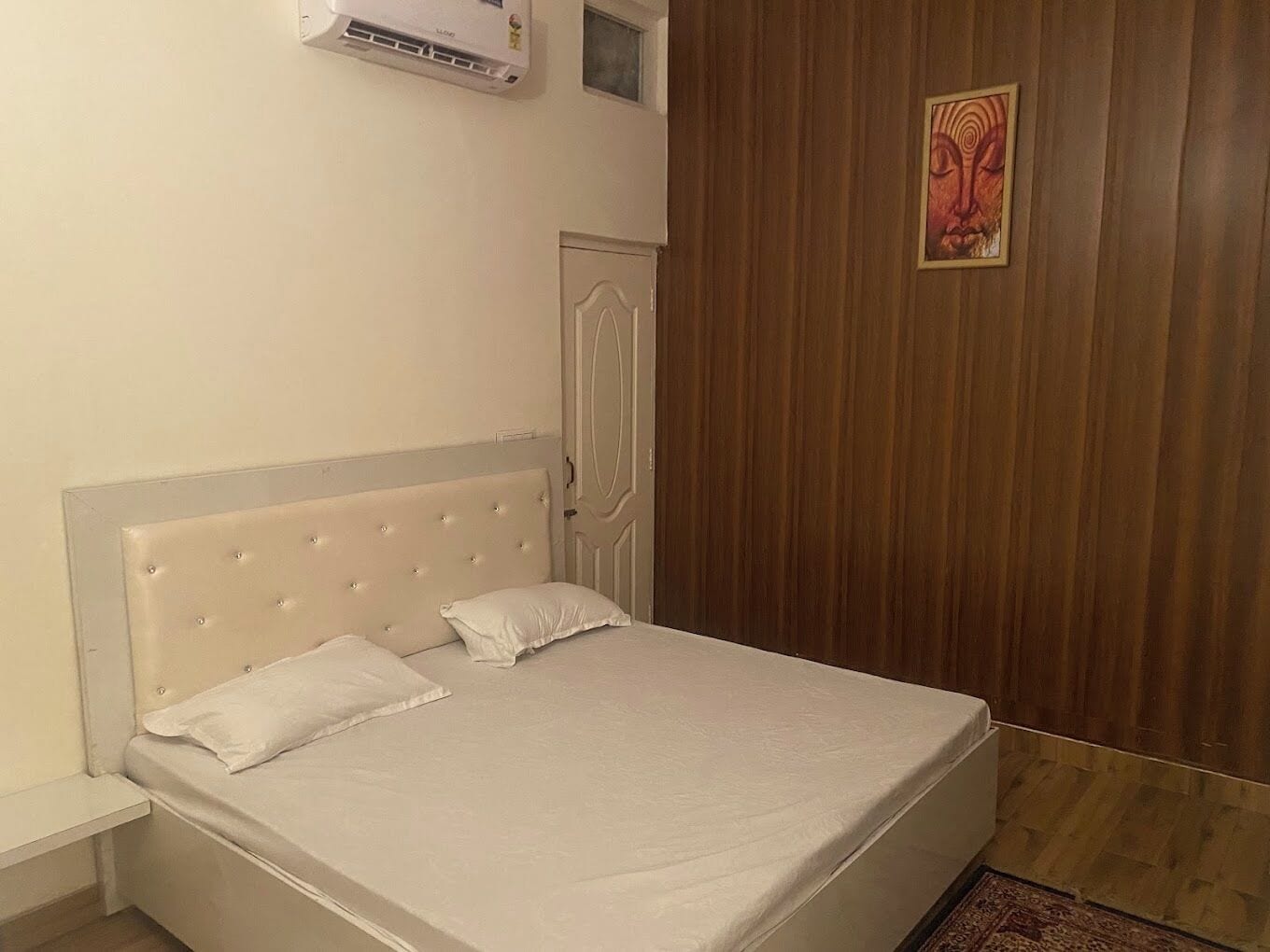Een slaapkamer met een bed, een houten garderobe en een airconditioning.