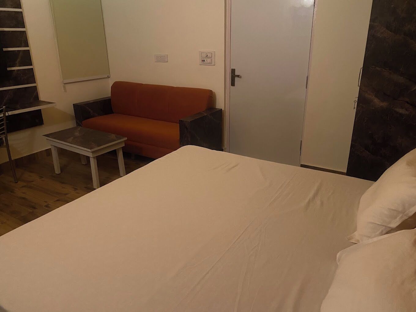 A room with a bed, a small table, a sofa, and a wardrobe.