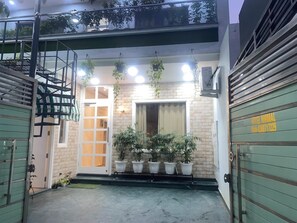 A hotel entrance with a glass door, potted plants, and a green awning. - Hotel Nirmal - Budget Friendly Rooms near Fortis Hospital and Marriage Palaces (Amritsar)