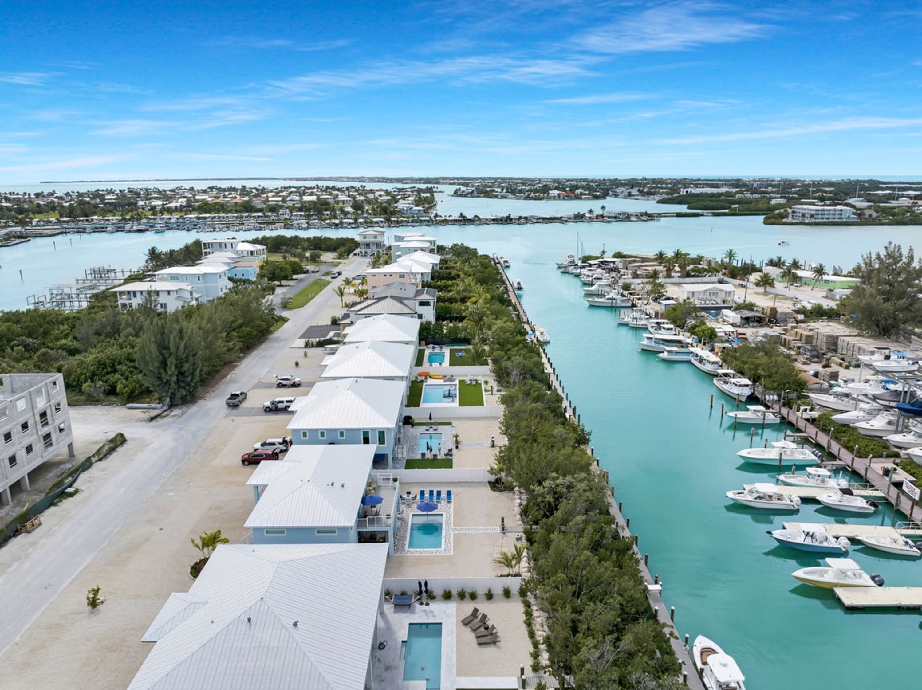 Un port de plaisance avec des bateaux amarrés, un espace piscine et une rangée de bâtiments dotés d’un toit plat.