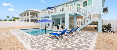 A two-story house with a swimming pool, outdoor seating, and a covered patio area.
