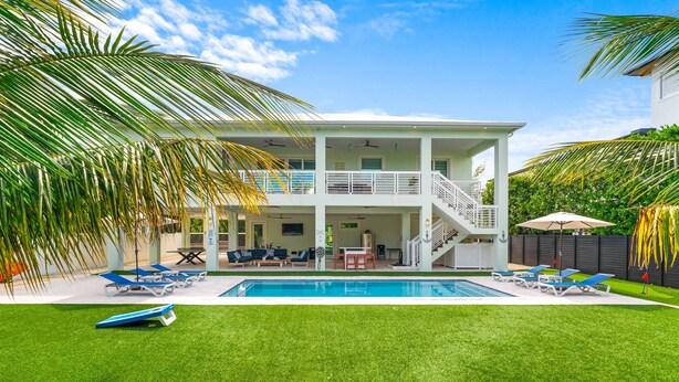 A two-story house with a pool, outdoor seating, and a staircase leading to the upper floor.
