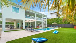 A modern house with a pool, outdoor seating, and a covered patio area.