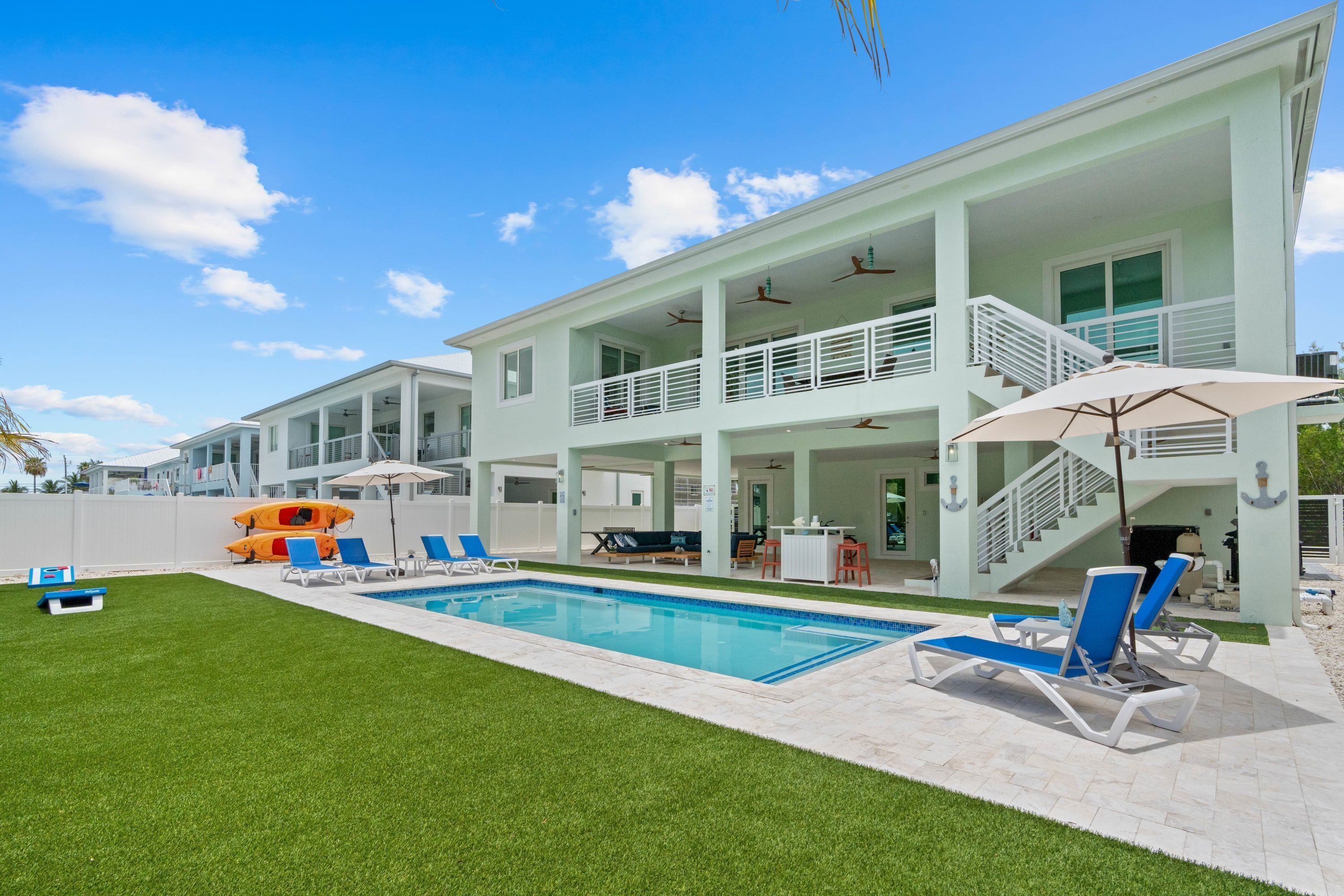 A two-story house with a swimming pool, outdoor seating, and a covered patio area.