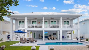 Ein zweistöckiges Haus mit Swimmingpool, Sitzgelegenheiten im Freien und einem Balkon.