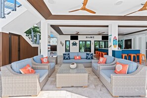 A modern living area with wicker furniture, a central coffee table, and a ceiling fan.