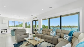 A modern living room with a sofa, coffee table, and a view of the ocean. - Luxury Seaside Escape Pool Dock Scenic Views (Marathon)
