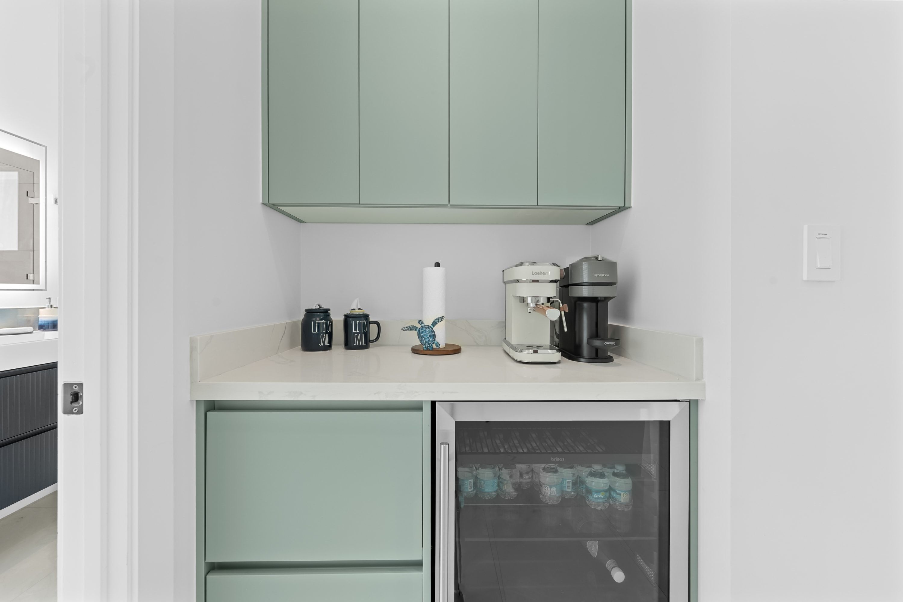 Eine Küchenzeile mit Kaffeemaschine, Wasserkocher und Kühlschrank.