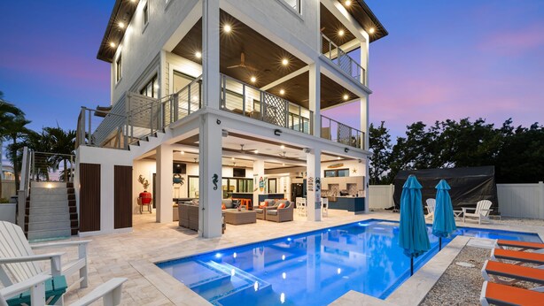 A modern two-story house with a swimming pool, outdoor seating, and a covered patio area. - Luxury Seaside Escape Pool Dock Scenic Views (Marathon)