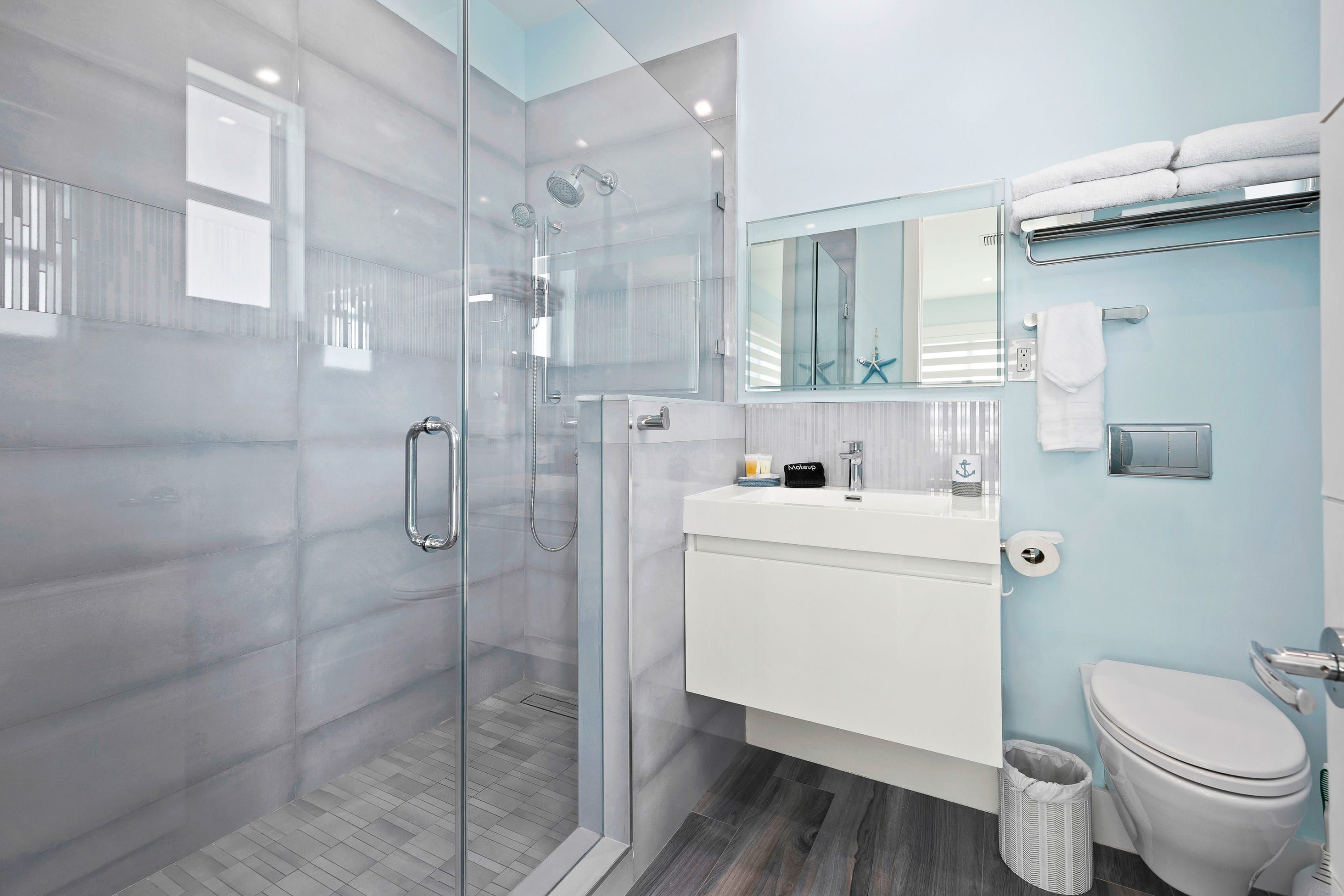 A modern bathroom with a glass-enclosed shower, a white sink, and a toilet.