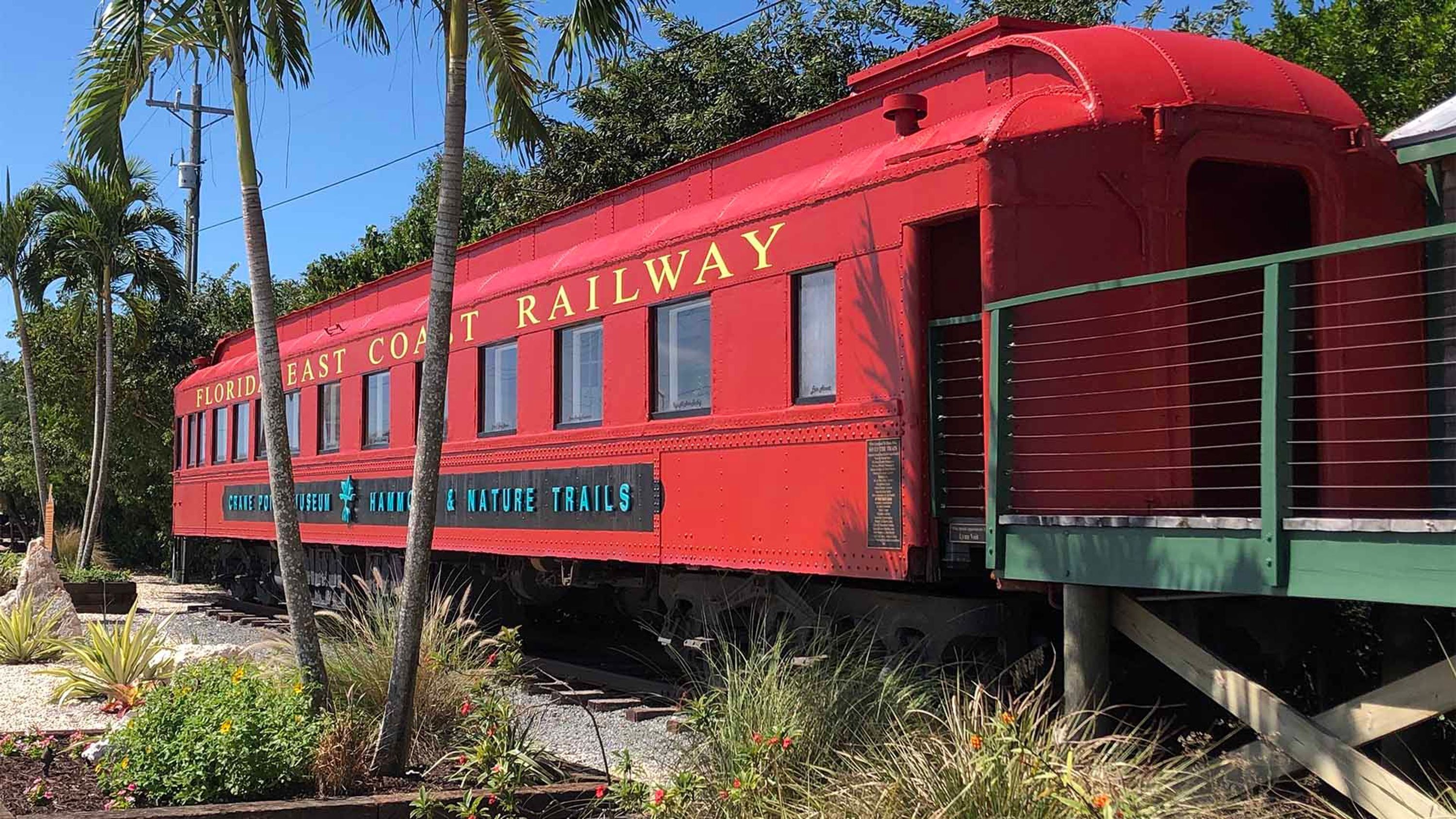 Un vecchio vagone ferroviario rosso della Florida East Coast Railway, con la scritta "CRANE POINT HARBOR & NATURE TRAILS" sul fianco.